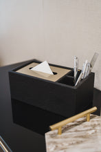 Granada black tissue box containing tissue and stationery on a black glossy table