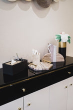 Granada black tissue box next to Preston brown marble tray, Hugo brown marble bookends and Pablo black and gold vase on a black and white side console