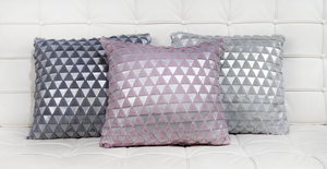 Bijou dark grey cushion next to Bijou pink cushion and Bijou light silver cushion on a white leather quilted sofa