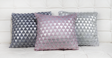 Bijou pink cushion with Bijou dark silver cushion and light silver cushion on a white leather quilted sofa