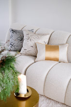 Beige Ansan cushion in between Brompton white and gold cushion and Ansan grey cushion on a cream boucle sofa.