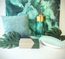 Styled photo of Adele vase together with other green-hued home decor accessories in front of a green marbled painting