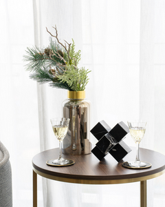 Styled photo of Andria Vase large with pine leaves and dried twigs. It is placed on a small walnut coffee table with wine glasses and black cube sculpture.