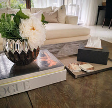 Styled photo of set of Aiden coasters stacked in front of a grey tissue box on a beige leather and metal tray, all placed on a wooden coffee table