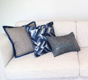 Beckett grey cushion with Bruno blue cushion and Seville blue and grey cushion on a light grey fabric sofa