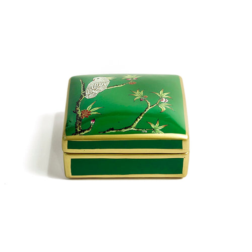 Front view of green Emery box with tree and bird motifs and gold borders on a green ceramic base