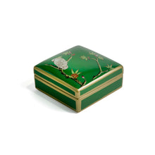 Side view of green Emery box with tree and bird motifs and gold borders on a green ceramic base