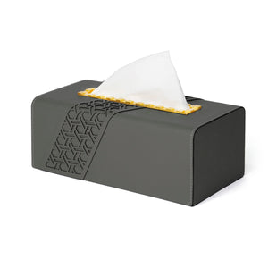 Side view of filled Tatum tissue box with geometric pattern on dark grey faux leather and yellow indented metal opening