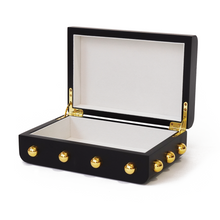 Side view of open Velletri box with a smooth black body, gold hardware and cream suede inner lining